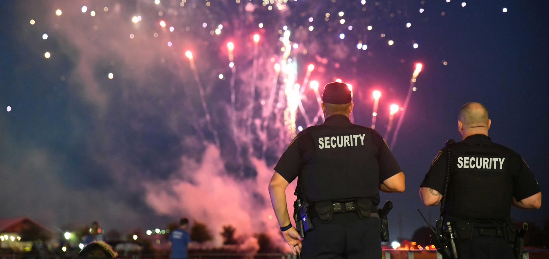 two security officers keeping watch with fireworks in the background