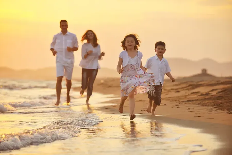family of four running on beach toward camera, sunset colors