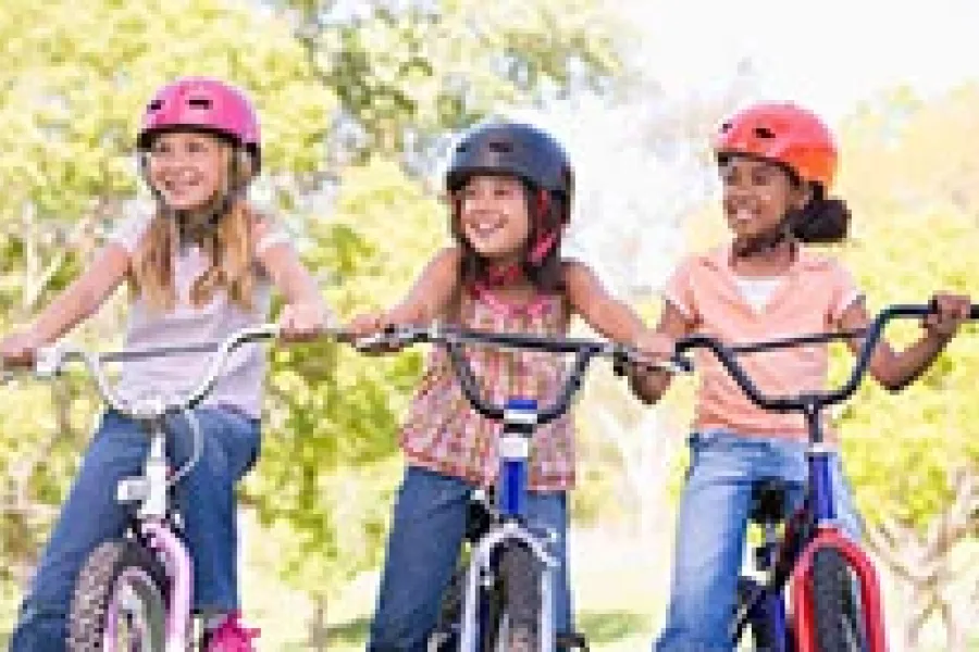 three girls riding bicycles wearing helmets