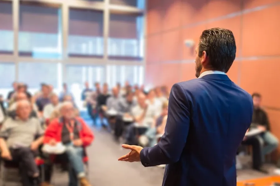 man giving presentation to large group inside