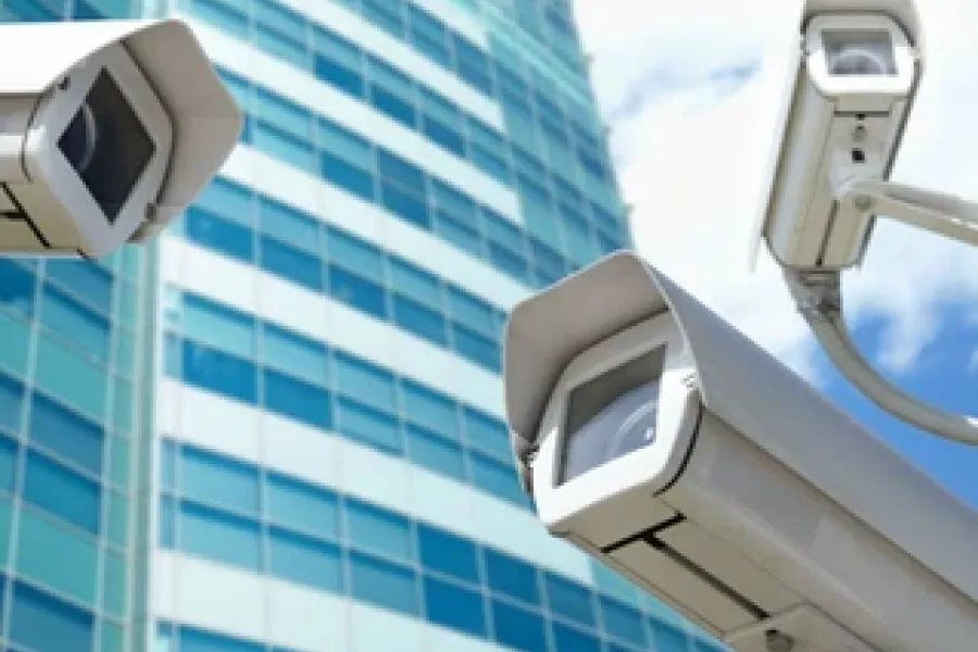 three security cameras with skyscraper in the background