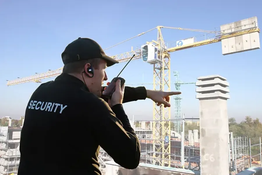 security guard talking into radio and pointing at construction site