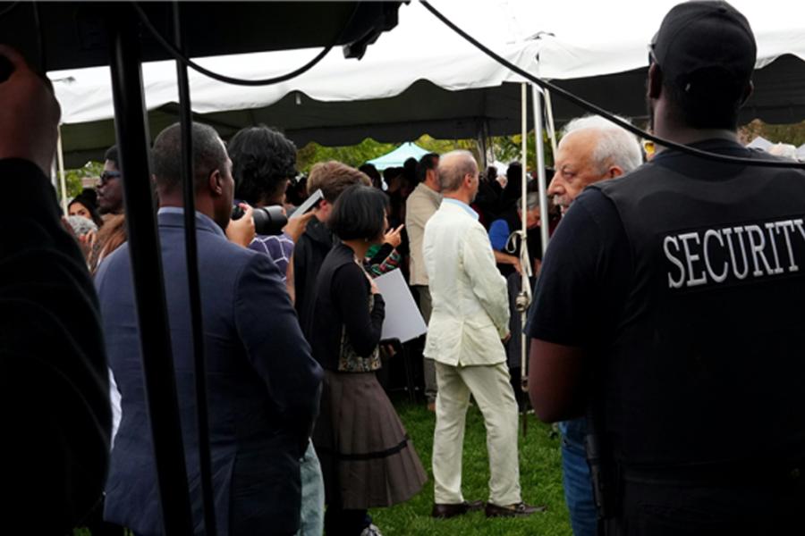 security officer observing outdoor gathering under tent