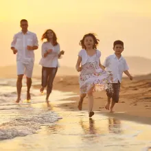 family of four running on beach toward camera, sunset colors