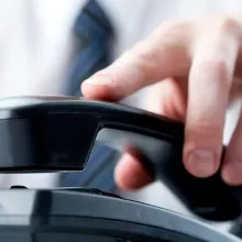 close up of hand picking up office phone on desk