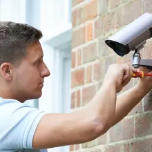 man installing security camera outside building