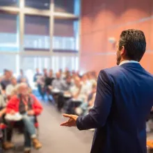 man giving presentation to large group inside