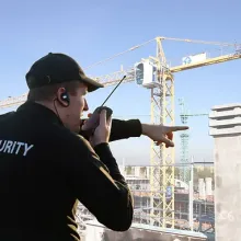 security guard talking into radio and pointing at construction site