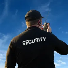 view of back of security officer talking into radio, set against bright blue sky