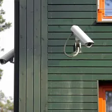 two security cameras mounted on green building angled down