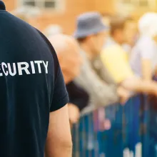 close up of back of security guard shirt standing outside at event, shirt says "security" on back