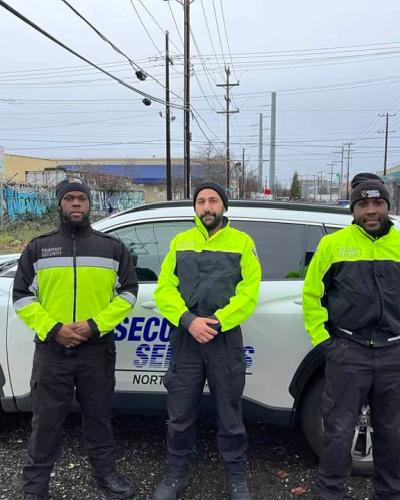 three transit security officers stand in front of patrol car