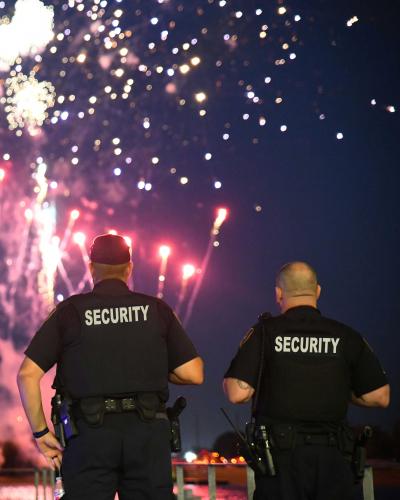 two security officers keeping watch with fireworks in the background