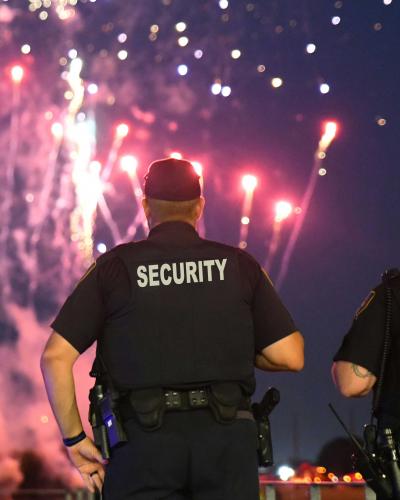 two security officers keeping watch with fireworks in the background