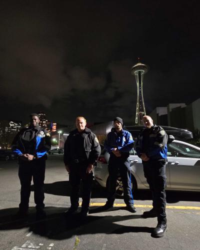 four officers in seattle space needle in background at night