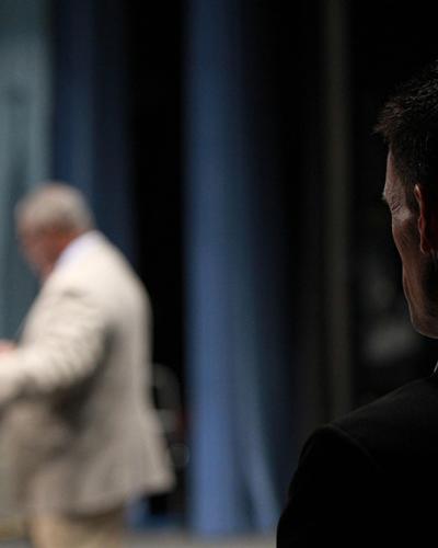 bodyguard standing backstage while speaker is on stage
